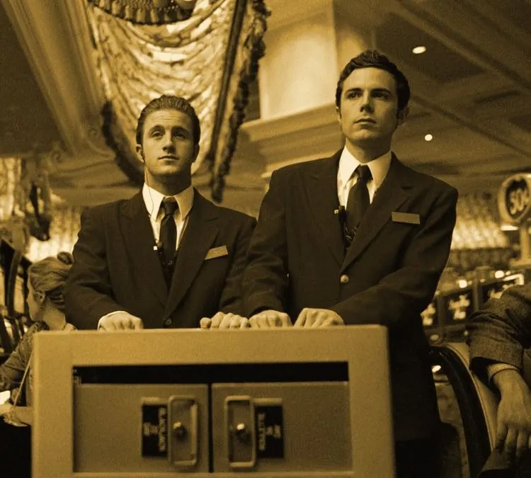 Two men in red hotel uniforms behind a counter
