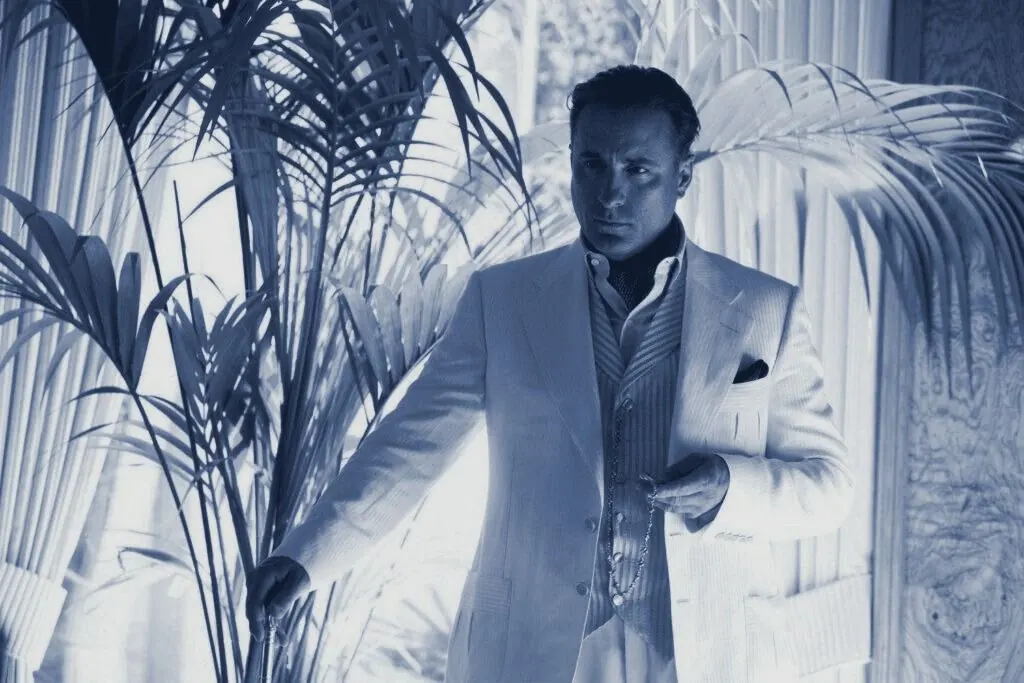Terry Benedict in a white suit among palms, cyanotype tone